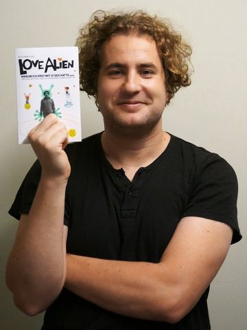 Wolfram Huke hält sein Buch „Love Alien“ in die Kamera